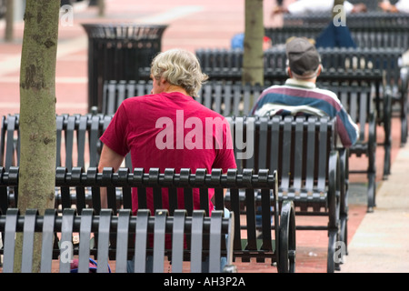 Men sitting outside on metal city benches Stock Photo