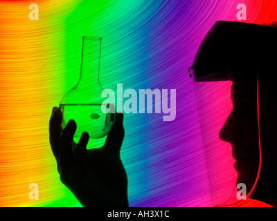 technician wearing face shield examining beaker of liquid Stock Photo