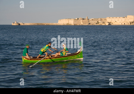 Regatta rowers in the Grand Harbour, Malta, with Fort Ricasoli in the distance Stock Photo