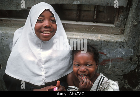 Happy Zanzibari girl wearing a muslim headcloth and her younger sister Stone Town Zanzibar Tanzania East Africa Stock Photo