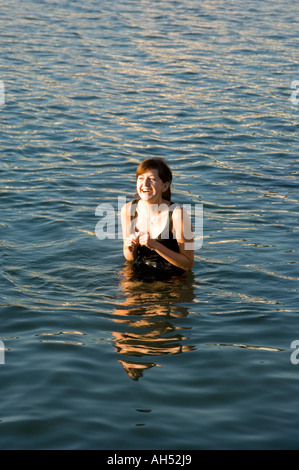 Slim dark haired smiling young woman standing in the sea Aberystwyth Cardigan Bay wales cymru summer afternoon sunshine Stock Photo