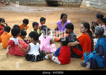 Indian School children sitting outside on the ground listening to their teachers Stock Photo