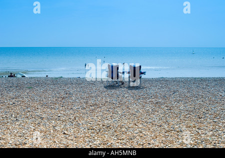 tourists sunbathing on pebble beach looking towards the sea Stock Photo