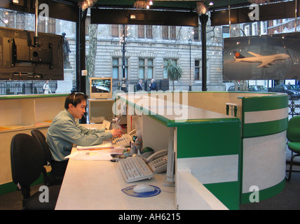 Man working from the desk of a travel agency in central London England Britain UK Stock Photo