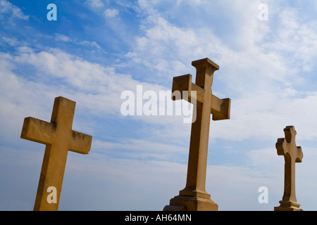 Three crucifix headstones shot against a dramatic blue sky Stock Photo