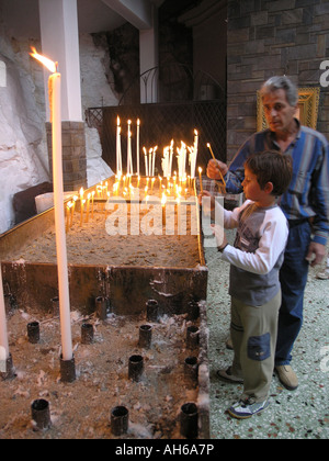 Father and son lighting candle in greek orthodox church Athens Greece Stock Photo