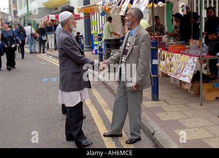 Two Asian men shaking hands greeting each other in Brink lane east london. Stock Photo