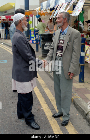 Two Asian men shaking hands greeting each other in Brink lane east london. Stock Photo