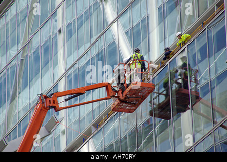 City of London new office block under construction glass cladding panels being checked from cherry picker truck mounted work platform England UK Stock Photo