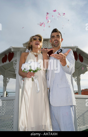 Low angle view of a bride and groom standing and throwing confetti Stock Photo