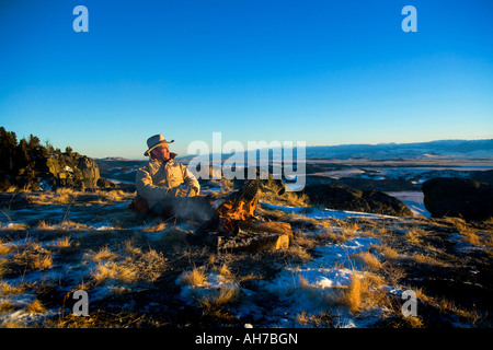 Mature man sitting in front of a campfire Stock Photo
