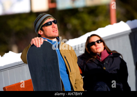 Mid adult man holding a snowboard with a young woman in the background Stock Photo