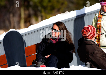Young woman sitting on a bench wearing sunglasses Stock Photo