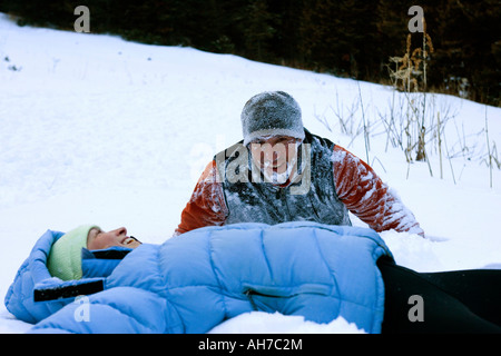 Mid adult woman lying in the snow with a mid adult man beside her Stock Photo