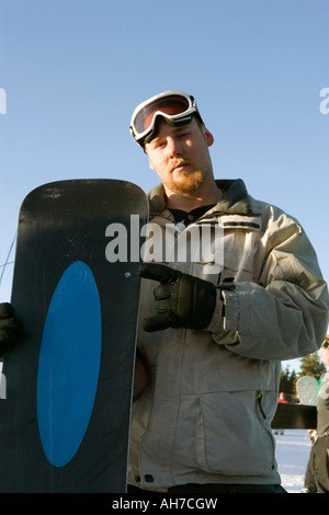 Low angle view of a man holding a snowboard and gesturing Stock Photo
