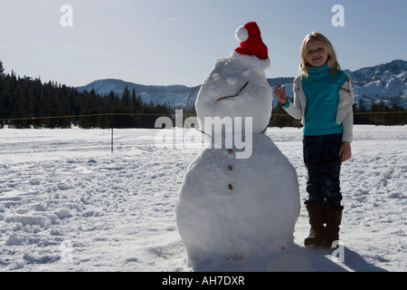 Girl standing next to a snowman Stock Photo