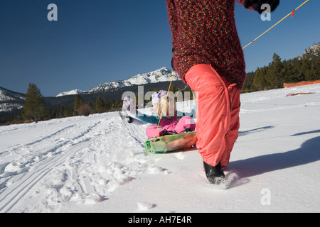 Mature woman pulling her daughters on a sled Stock Photo