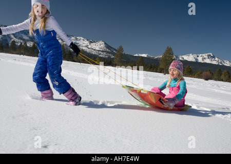 Girl pulling her sister on a sled Stock Photo