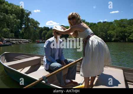 Young woman standing on a boat and putting a cap on a young man's head Stock Photo