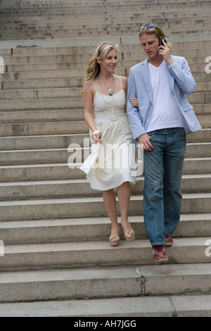 Young man talking on a mobile phone and moving down a staircase with a young woman Stock Photo