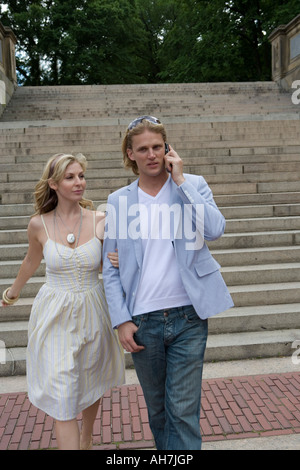Young man talking on a mobile phone and walking with a young woman Stock Photo