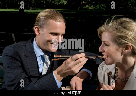 Young man feeding sushi to a young woman with chopsticks and smiling Stock Photo