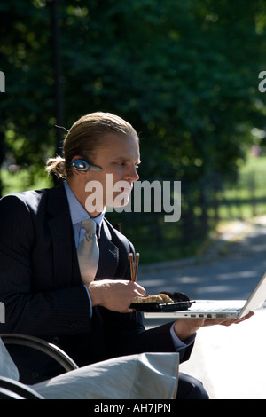 Businessman sitting on a bench and looking at a laptop Stock Photo