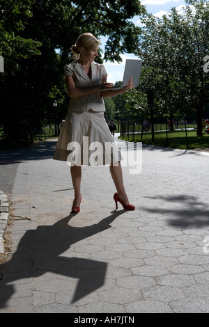 Young woman using a laptop and standing on a path Stock Photo