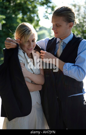 Young man putting his coat around a young woman's shoulders Stock Photo