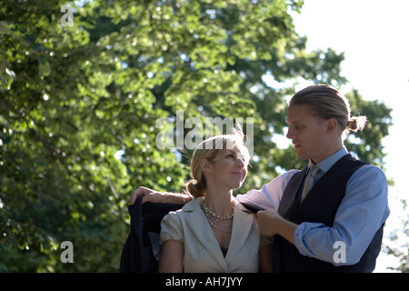 Young man putting his coat around a young woman's shoulders Stock Photo