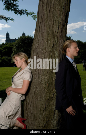 Young couple leaning against a tree Stock Photo