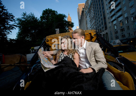 Young couple riding in a horsedrawn carriage and looking at a road map, Central Park, Manhattan, New York City, New York, USA Stock Photo
