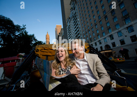 Young couple riding in a horsedrawn carriage and looking at a road map, Central Park, Manhattan, New York City, New York, USA Stock Photo