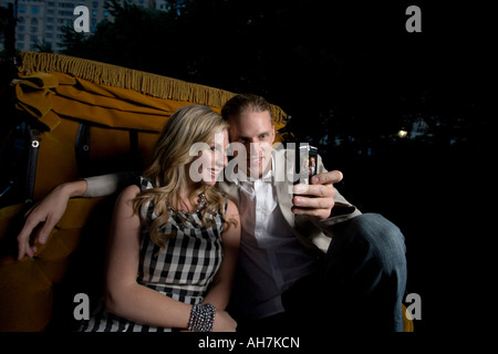 Young couple riding in a horsedrawn carriage and taking a picture of themselves with a mobile phone, Central Park, Manhattan, Ne Stock Photo