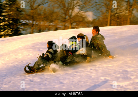 Family riding toboggan down fairway of Town and Country Golf course. St Paul Minnesota USA Stock Photo