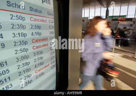 A passenger hurries past a flight schedule display at Logan International Airport in Boston Massachusetts Stock Photo