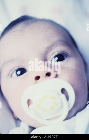 Portrait of four week old baby boy looking curiously at the camera. Washed out, cool tones. Stock Photo