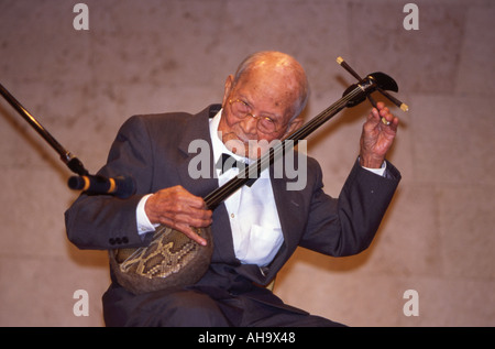 Elderly Okinawan man with sanshin in traditional yukata at Ryukyu Mura ...