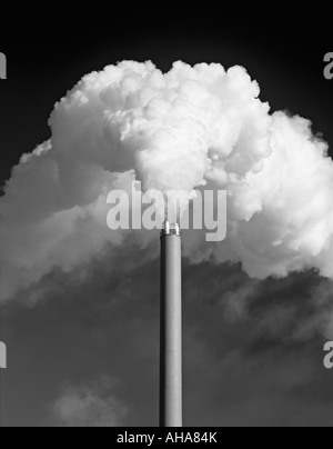 UK. A factory chimney emitting a huge plume of white smoke against a dark sky, monochrome Stock Photo