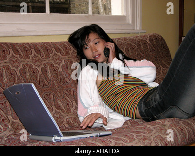 oriental woman relaxing on mobile phone and using laptop computer Stock Photo