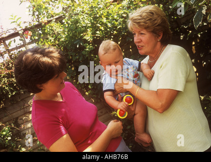 Baby boy outdoors with his mother and grandmother giving advice, U.K. UK Stock Photo