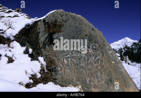A living faith mantras or sacred syllables being painted on a boulder on the wayside to Ngawal village Annapurna Area Nepal Stock Photo