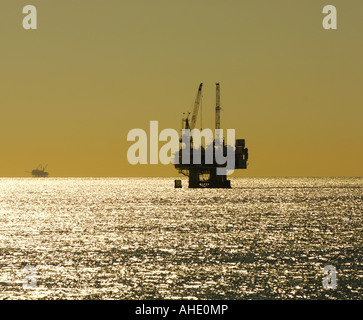 Silhouette of an offshore petroleum oil drilling platform at sunset as viewed from the Seal Beach Pier in Seal Beach, CA, USA