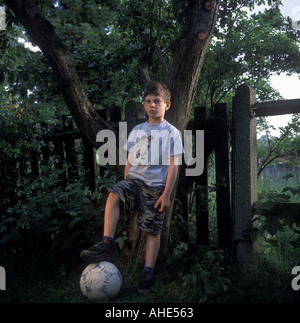 A six year old boy stands with his football in his parents garden, London, UK. Stock Photo