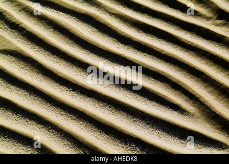 A strongly patterned art image of ripples in a sandy beach with strong sunlight creating lines that flow across the image Stock Photo