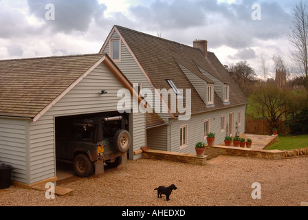 A TIMBER FRAMED HOUSE WITH A BLACK TERRIER DOG ON THE DRIVEWAY Stock Photo