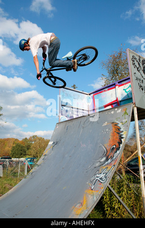 a young boy jumping with his bike on a quarter at a skatepark Stock Photo