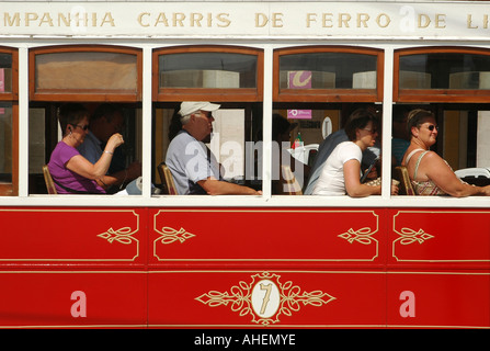 Tourists siting in an antique Lisbon red tram used for sightseeing tours in Praca do Comercio square, Lisbon Portugal Stock Photo