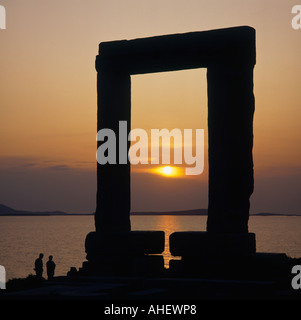 Sunset through the marble square arch of the Temple of Apollo with couple at base and sea beyond Naxos Island Greek Islands Stock Photo