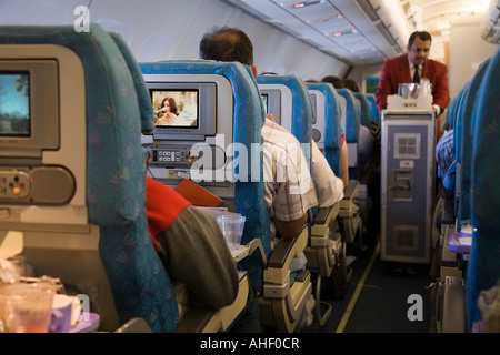 Cabin crew steward / flight attendant in the cabin aisle serving passengers on a SriLankan flight from London to Columbo. Stock Photo